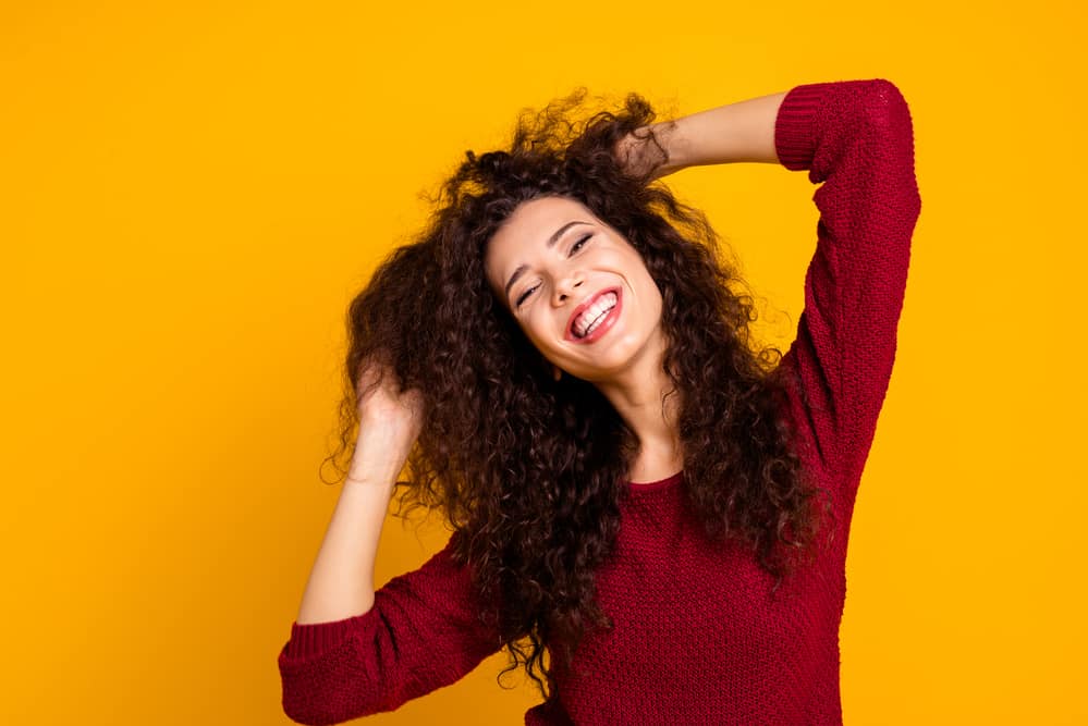 Lady dancing with permanent waves on medium length hair due to a multi-textured perm