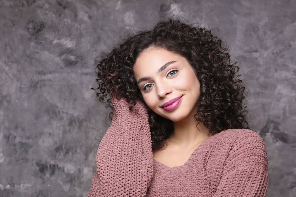 Woman with curly brassy hair toned with purple shampoo