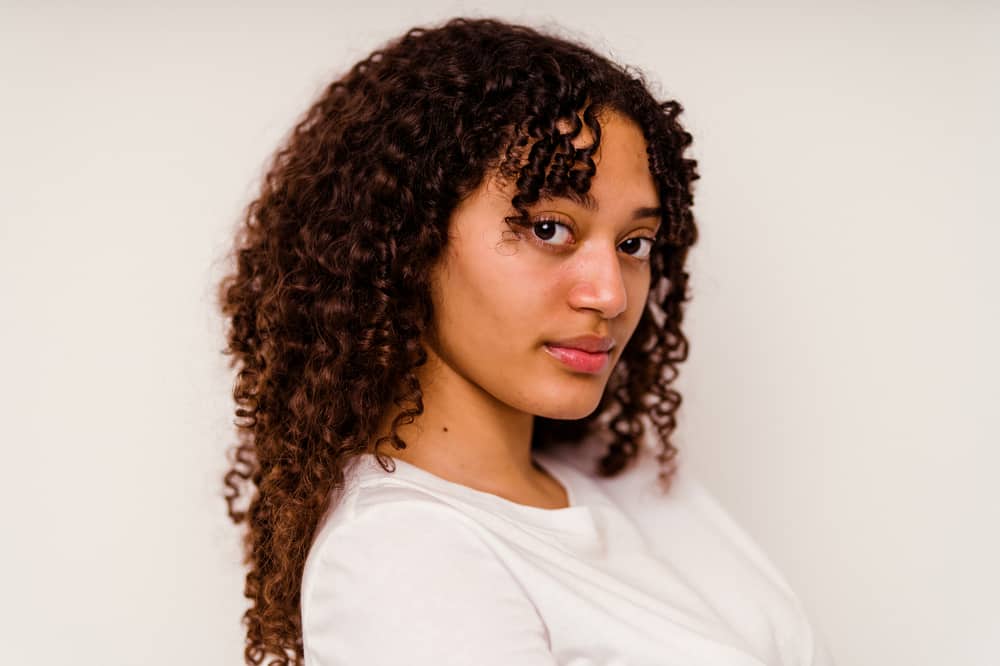 Young mixed race woman with natural lashes, natural mascara, black eyeliner, and curly hair strands
