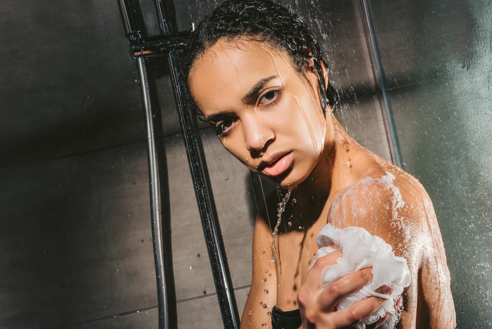African American woman using shampoo as both a body wash and body soap to remove dead skin cells