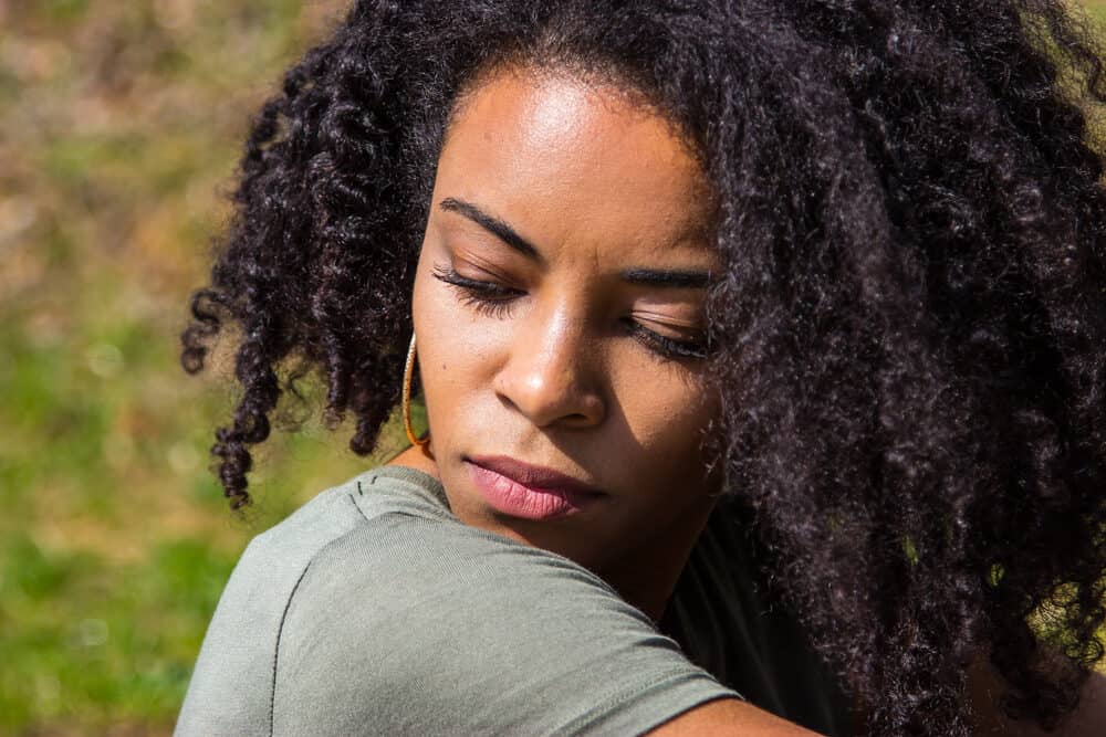 Black girl looking away while relaxing outside after a smoothing keratin treatment on her natural curls