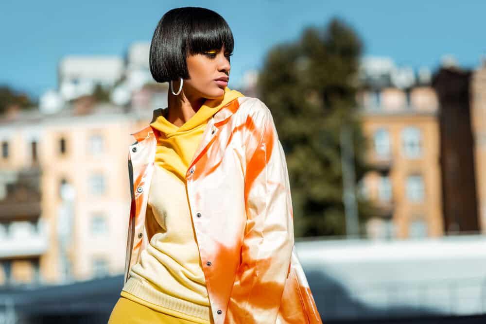 Female with a type 3c hair type and a bad cut wearing a colorful orange jacket