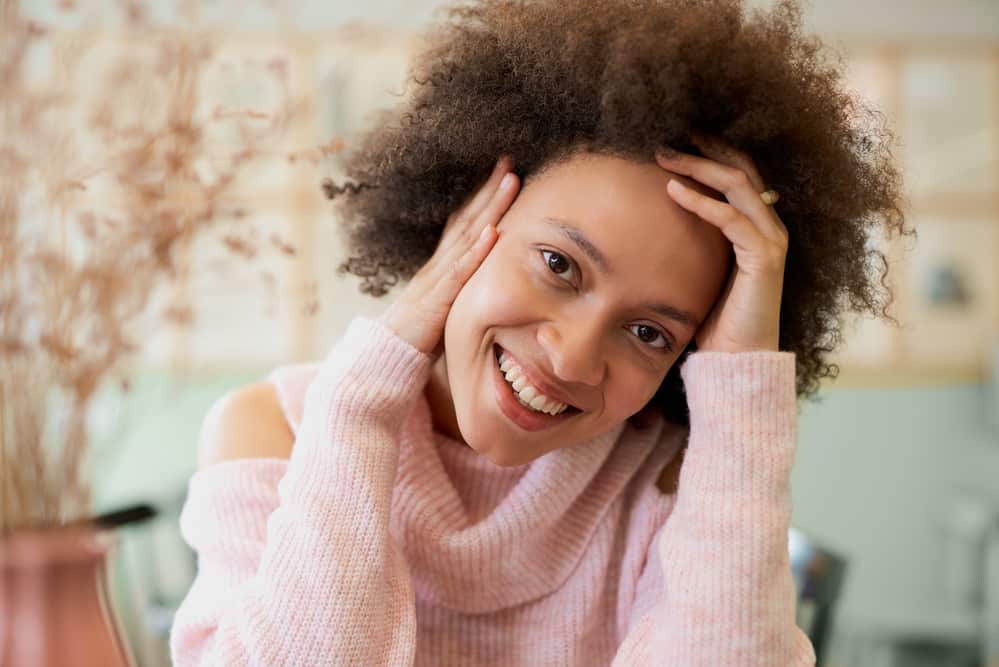 Black lady with greasy hair strands rubbing her fingers through her hair