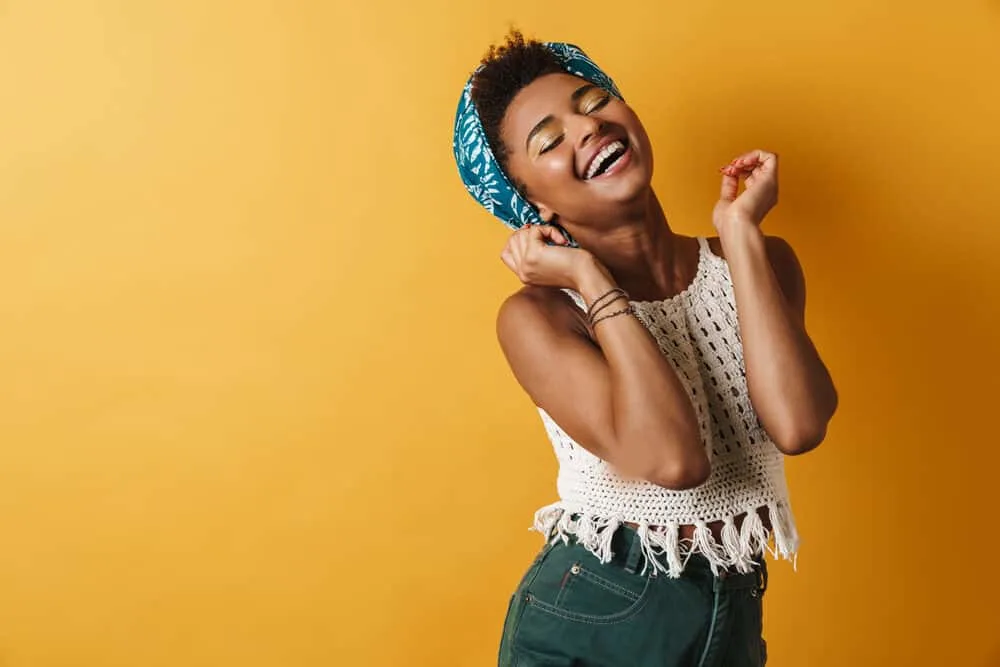How To Get Dandruff Out of Curly Hair Quickly at Home 5 African American woman dancing while wearing a satin head scarf to keep her scalp moisturized