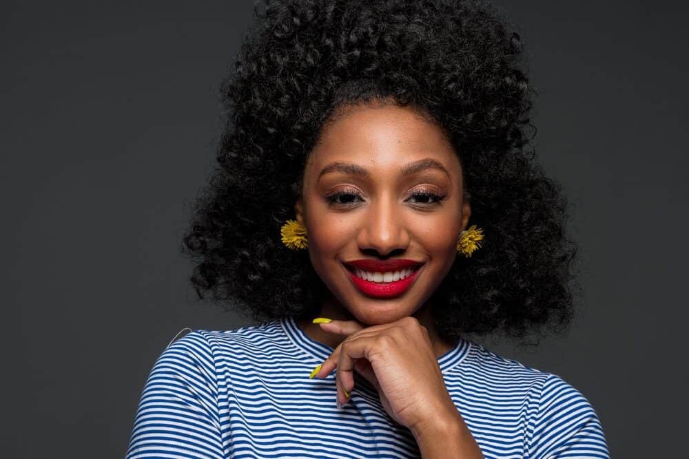 Pretty African American female with virgin hair wearing gold earrings and fingernail polish