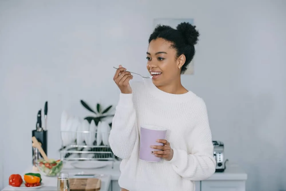 Afro Puffs Tutorial: ‘How to Do' Styling for Natural Hair: Complete Guide 9 Lady wearing a white sweater while eating ice cream from a bowl