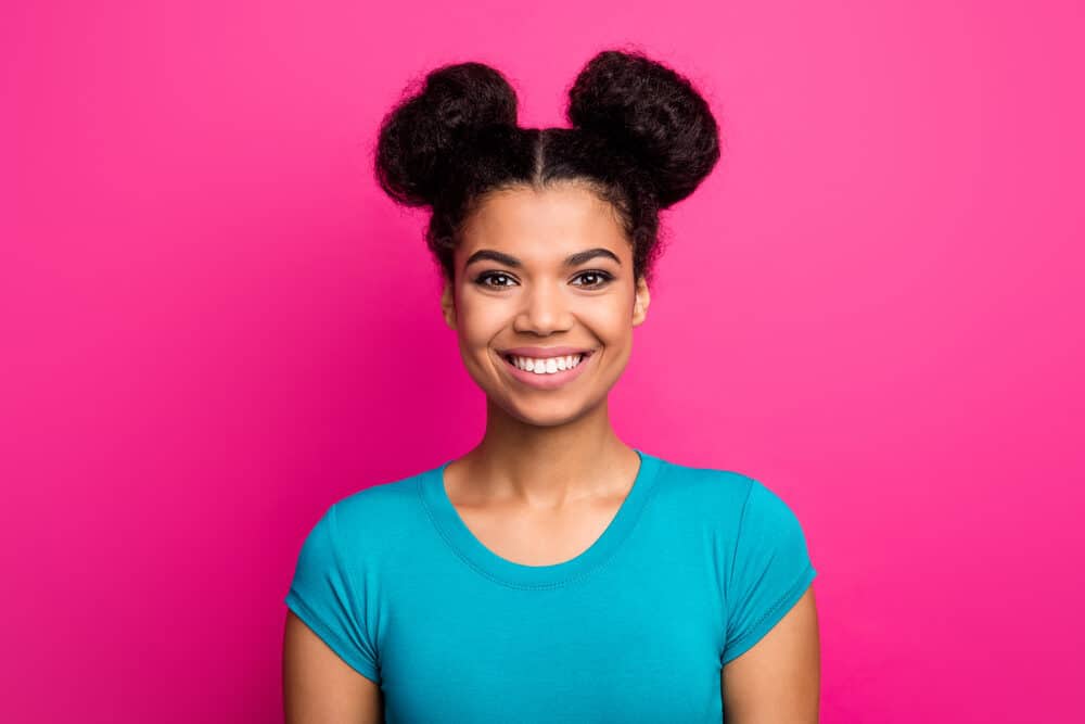 Cute African American female wearing a blue shirt with half-up space buns