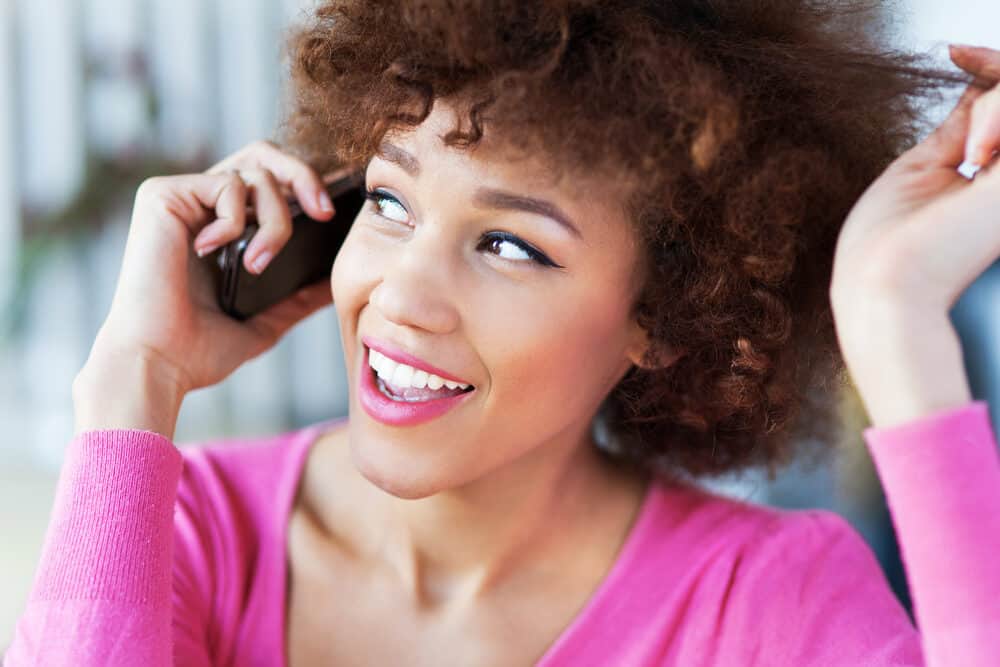 Girl talking on the phone wearing a purple shirt after using deep conditioning hair mask