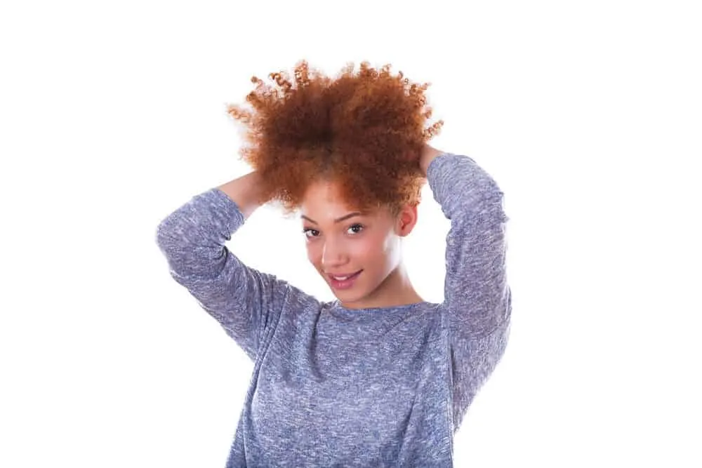 Young black lady with a red hair color wearing a blue and white sweater