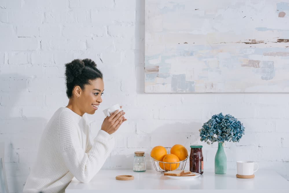 Lady drinking coffee at breakfast wearing a flat twist style on kinky hair