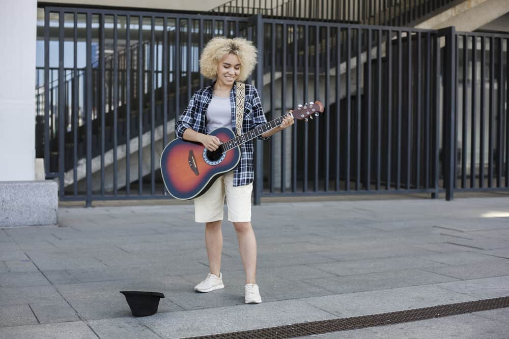 Female street musician with light ash blonde hair getting ready to perform at a concert