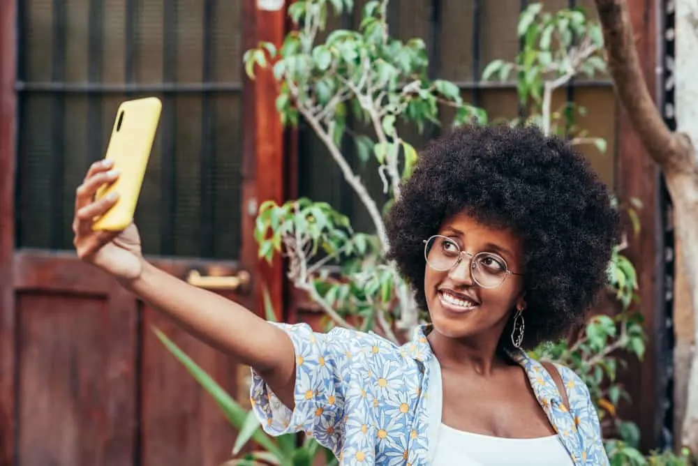 The 4 Best Hair Growth Products For African American Hair Types 8 Attractive woman taking a selfie of her curly hair after using a leave-in conditioner and organic shea butter to make her hair soft