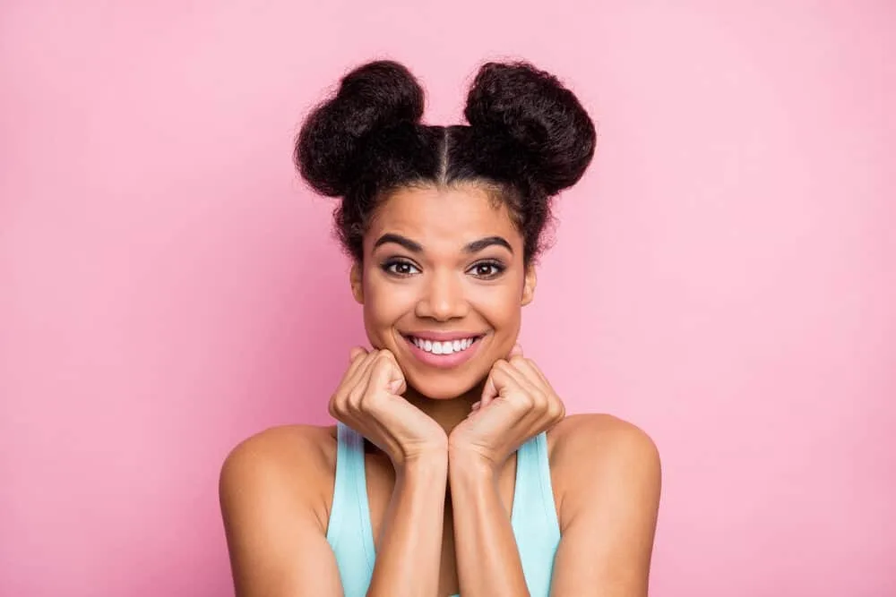How to Do Space Buns: Easy, Step-by-Step Tutorial for Beginners 4 Lady wearing two small space buns with a center part secured with clear hair elastics