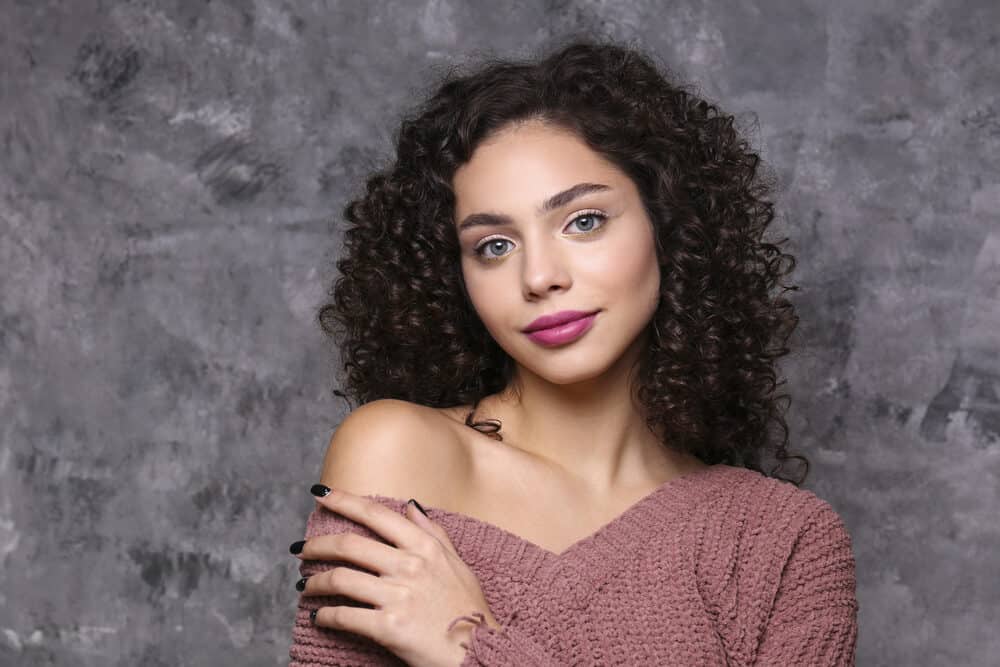 Cute lady with curly brassy hair, pink lipstick, and black fingernail polish