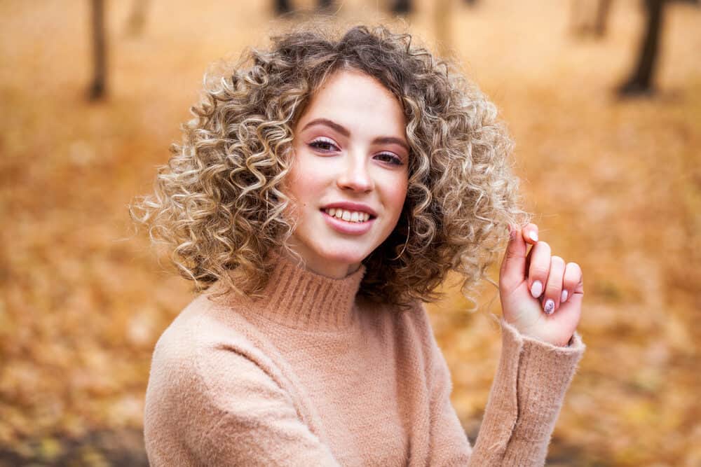 Young female with crazy curls sitting outside of an autumn day