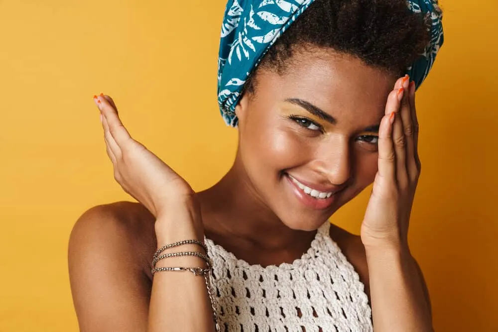 Happy black woman wearing a blue bonnet to retain her scalp's natural oils