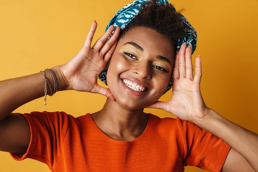 Gorgeous black woman with curly coarse hair wearing an orange t-shirt