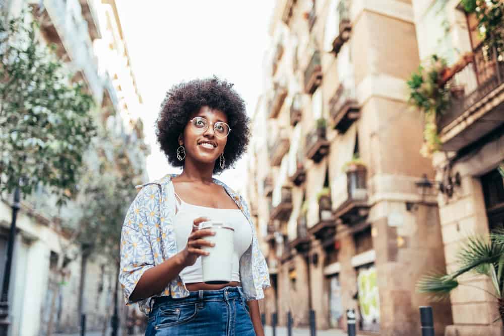 African female drinking coffee outside with dull hair and itchy scalp