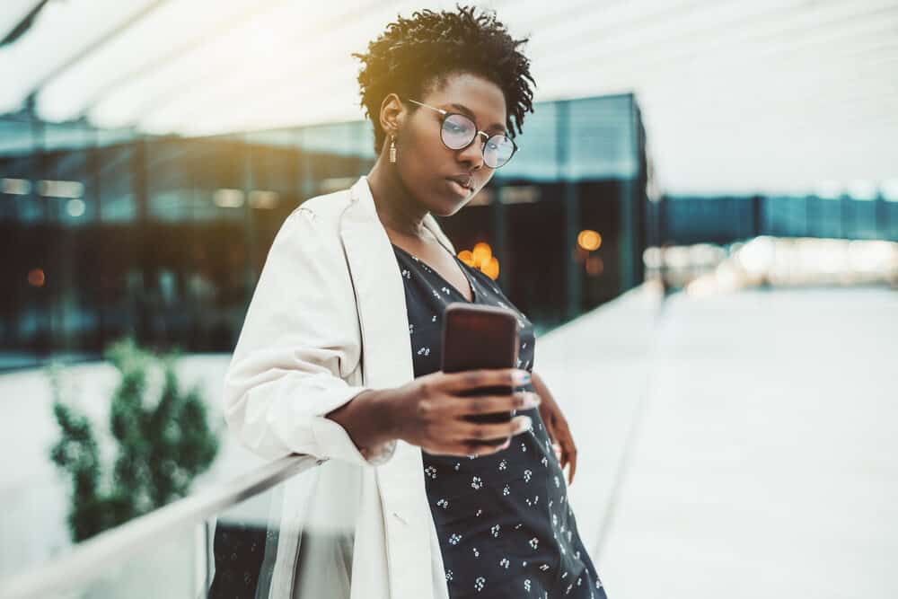 Young black female with two-strand twists locs with a 4C curl pattern taking a selfie on her cell phone