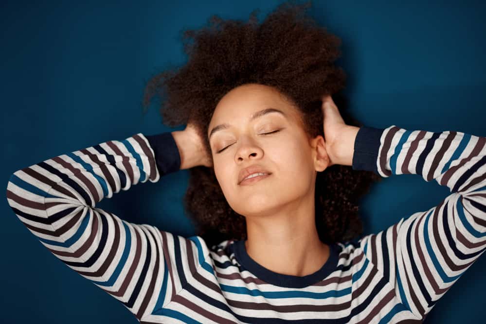 Black girl with shiny hair and sensitive scalp wearing a striped shirt