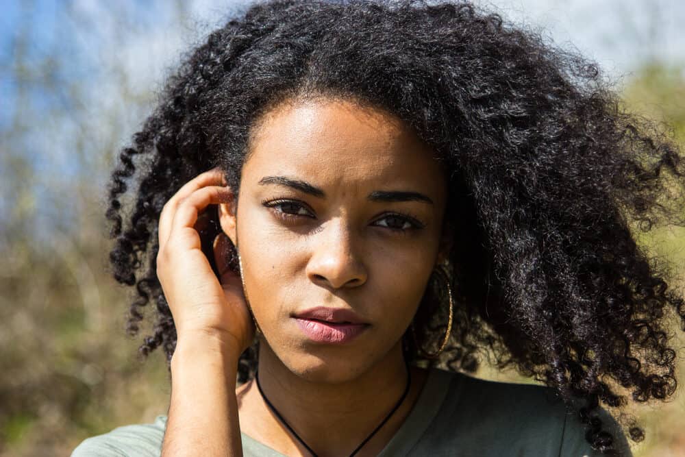 Pretty black woman with silky smooth hair posing for a photo on an autumn day