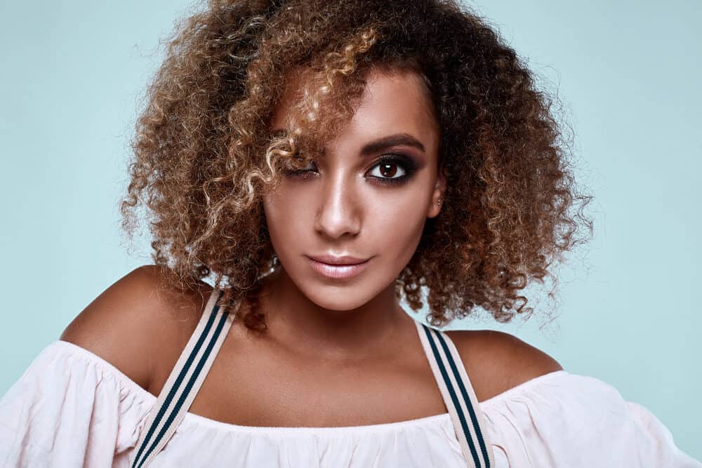 African American female with naturally wavy textured hair wearing a white dress shirt and natural make-up