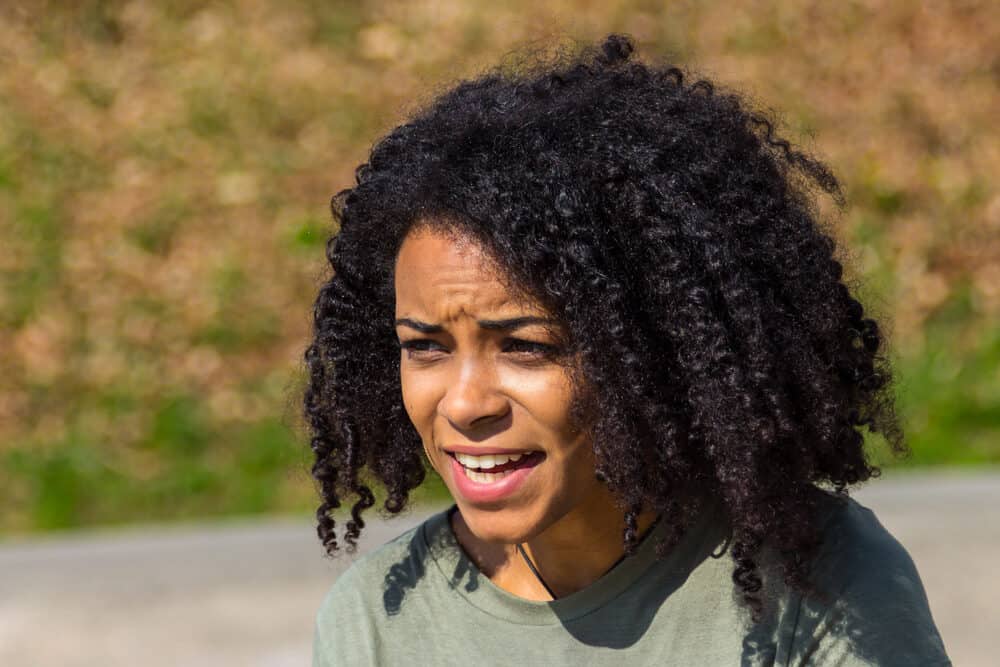 Lady with African American hair that includes kinks, coils, and curls talking to a friend outdoors