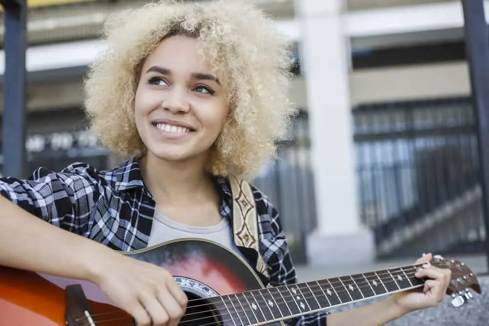 Putting Ash Blonde Over Bleached Hair: Can You Do It? What Happens? 1 African American girl with ash blonde hair dye playing the guitar outside