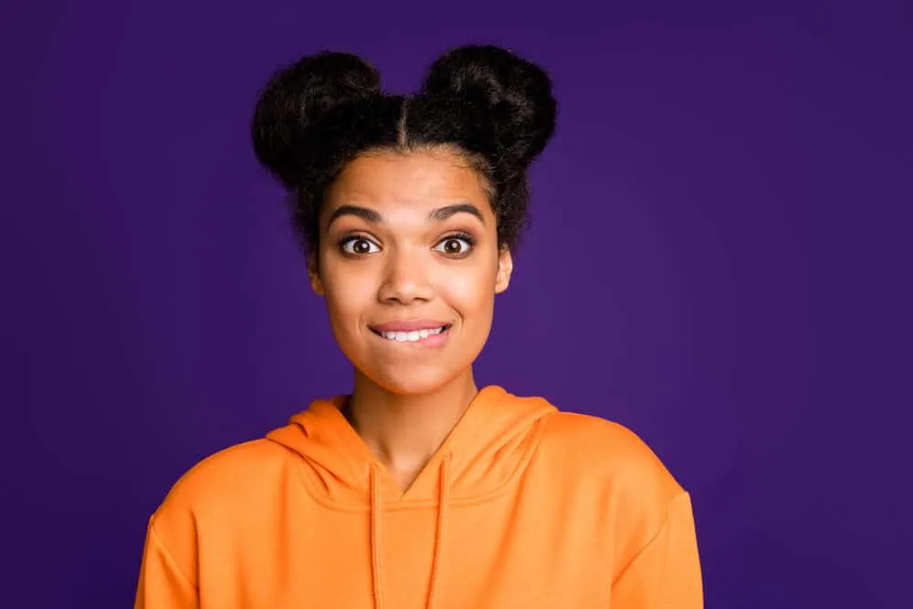 Black girl wearing a hoodie looking nervous while wearing a space bun style