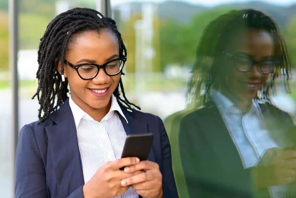 The 5 Different Stages of Locs: Baby, Budding, Teenage, Mature, and Rooted 6 Lady using a cell phone with teen stage faux locs reading about the five stages of locs