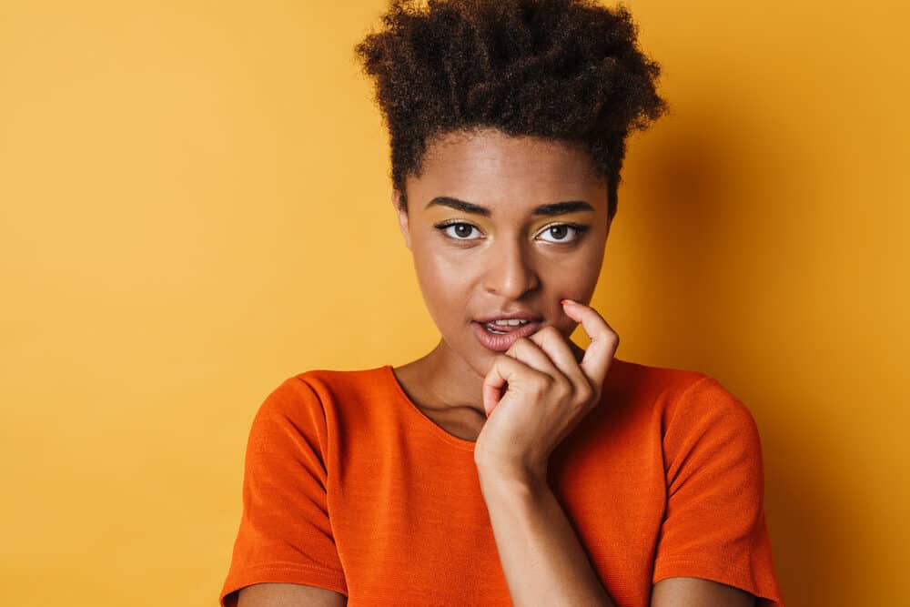 Black lady with naturally curly hair strands wearing pink lipstick