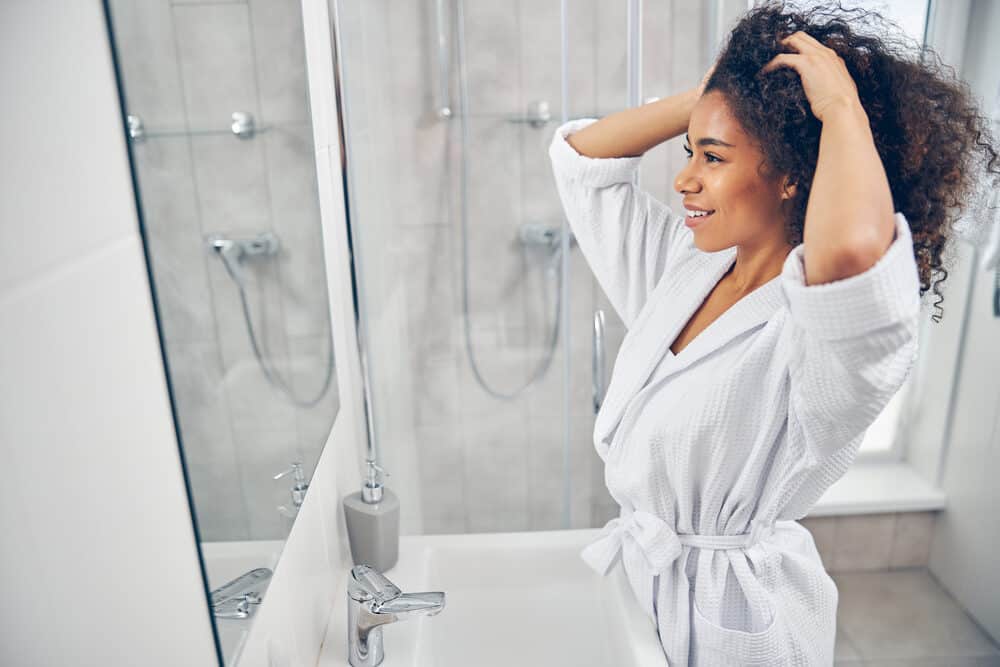 Beautiful young black girl air drying hair quickly after soaking strands in the shower