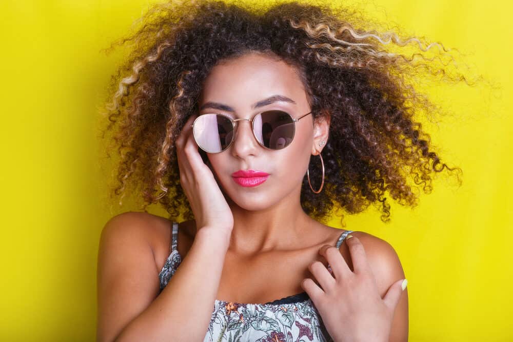 Beautiful light-skinned black girl with naturally curly hair wearing sunglasses and a colorful dress