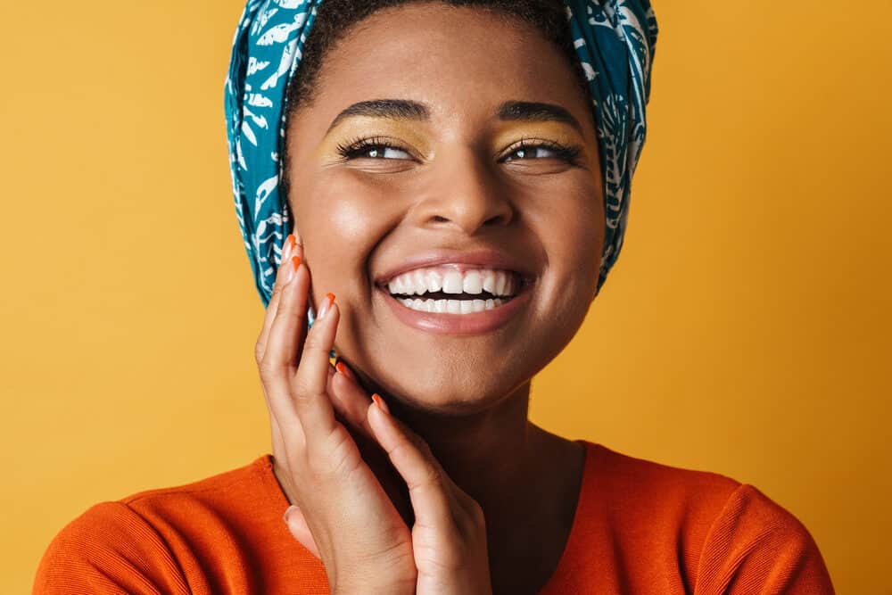 Black girl protecting wearing a scarf to protect her hair health from the sun's rays