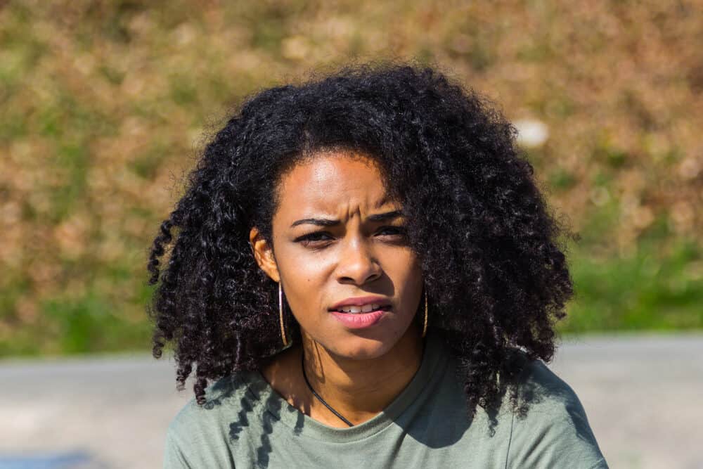 Attractive black lady with natural black hair wearing gold earrings and a green shirt