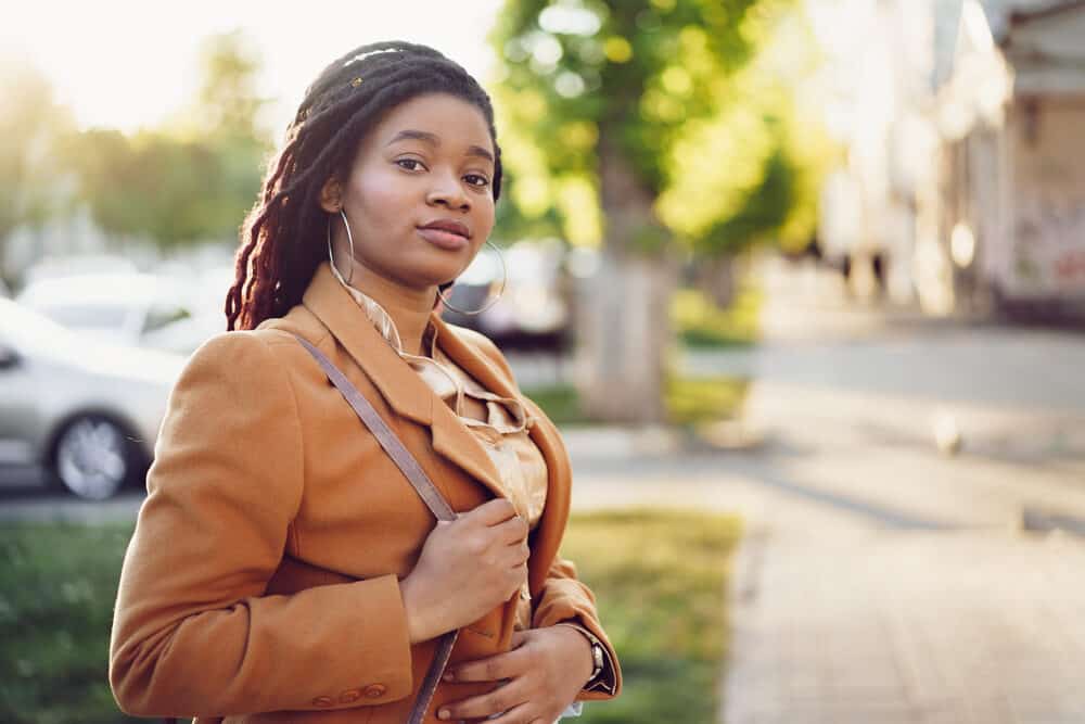 Black woman with loose hairs flying in the wind on her starter locs