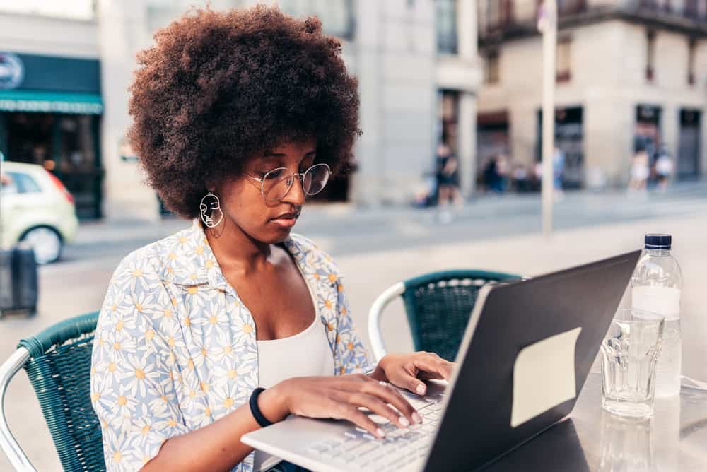 African American woman using an Apple MacBook Pro to Mielle Rosemary Mint Scalp