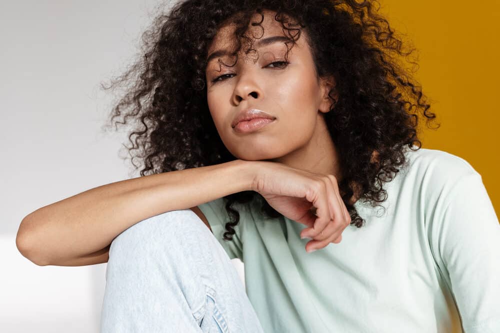 Cute African American woman with a type 3 curl pattern wearing a green shirt and jeans