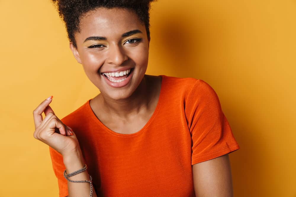 Cute black lady smiling washing her hair to remove silicone residue from each hair cuticle