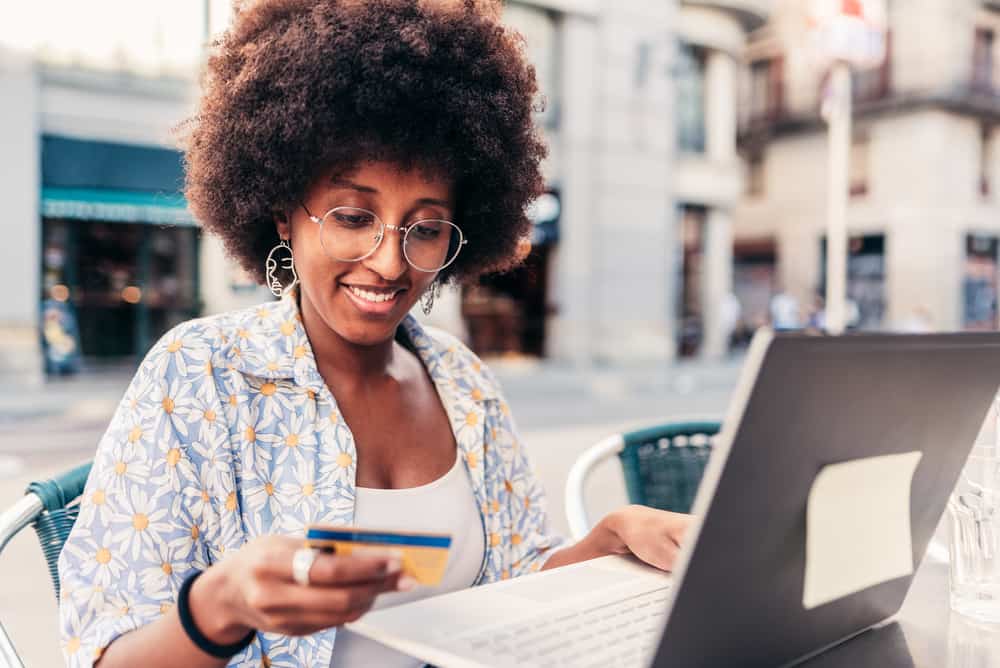 Black woman with an afro using her laptop to order a coconut cowash cleansing conditioner