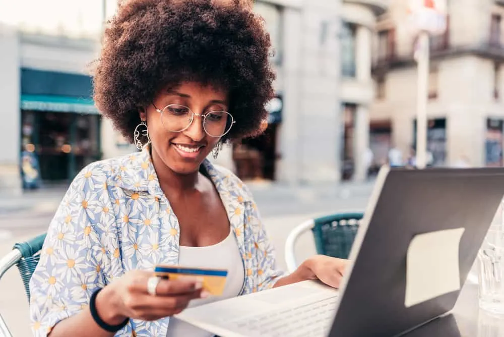 The 4 Best Hair Growth Products For African American Hair Types 7 Black woman with an afro using her laptop to order a coconut cowash cleansing conditioner