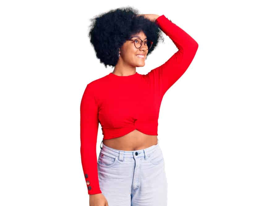 Young African American girl wearing a red shirt and blue jeans with curls treated with argan oil