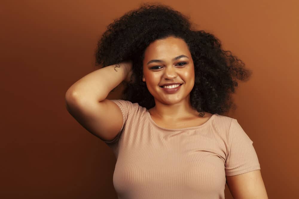 African American woman with a curly hair type wearing a brown shirt