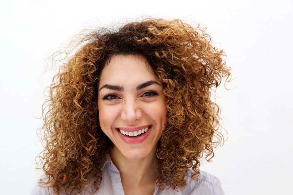 Young white lady with a darker hair color and brassy tones on naturally wavy hair