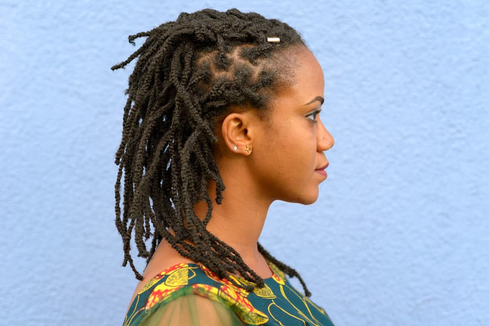 Black lady showing her dreadlocks after using a rosewater solution with coconut essential oil as a hair treatment