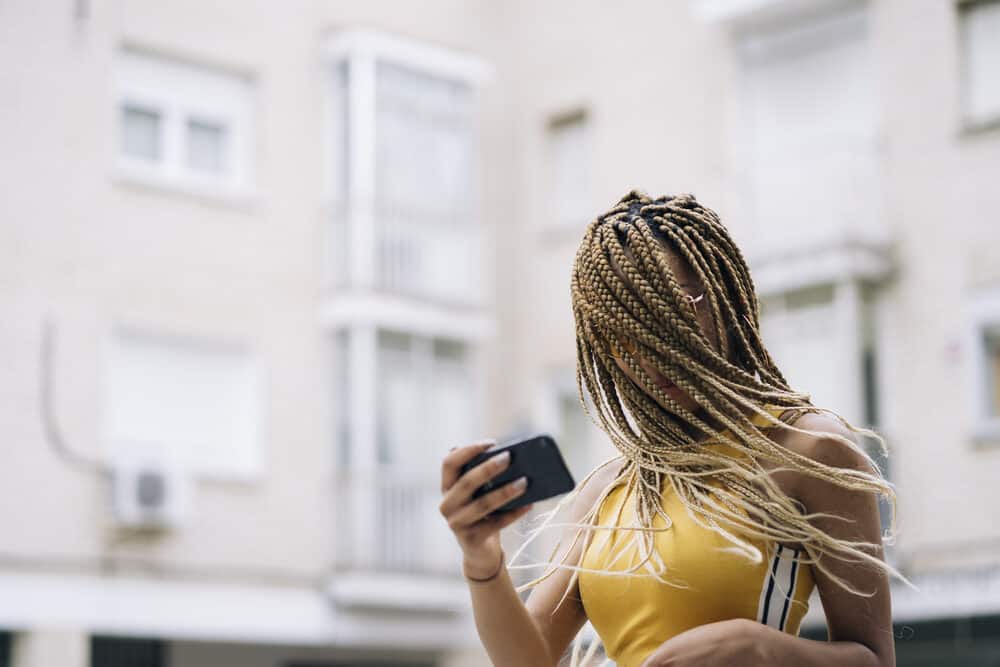 Black lady with braided stray hairs blowing in the wind experiencing slight frizz