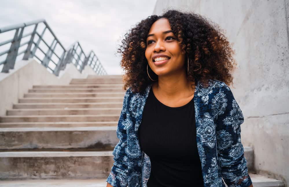 Cute African American girl with damaged hair strands sitting outside