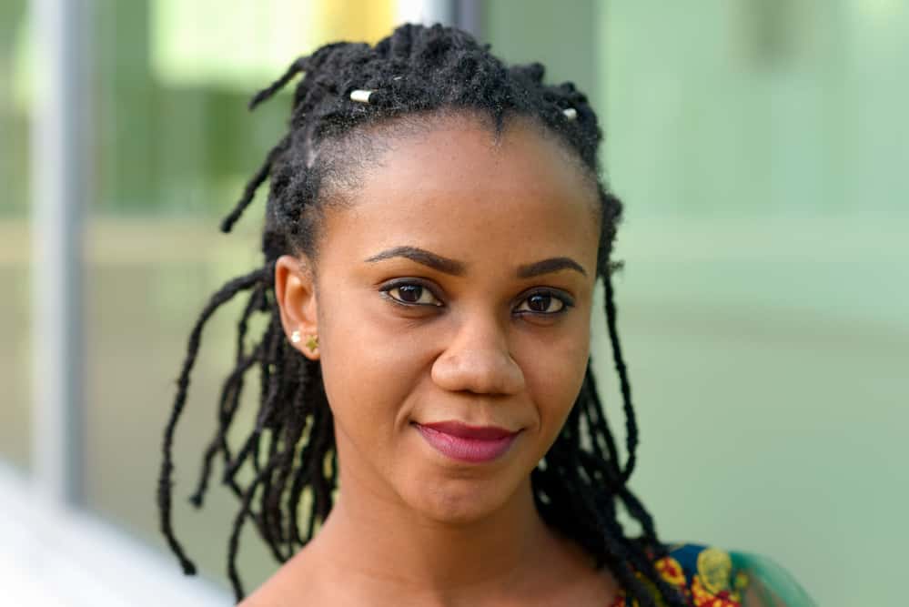 Pretty African American female with dreads after using rose water and dried rose petals to treat her locs