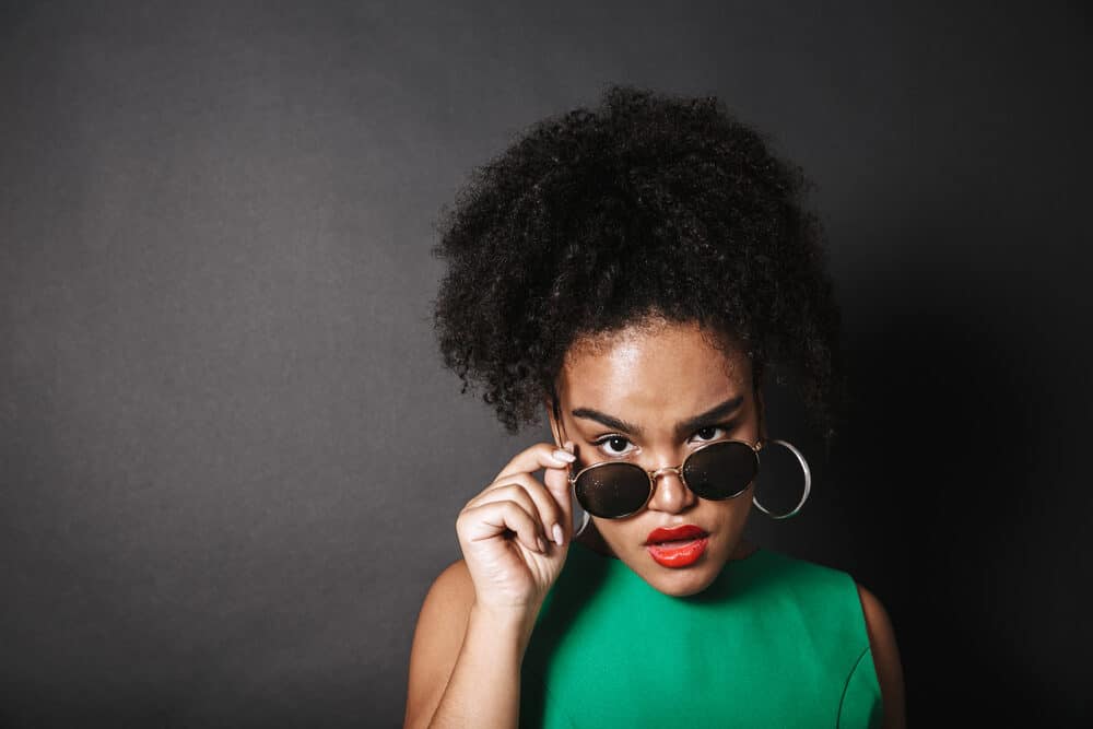 African woman wearing sunglasses with curls in a pineapple hairstyle