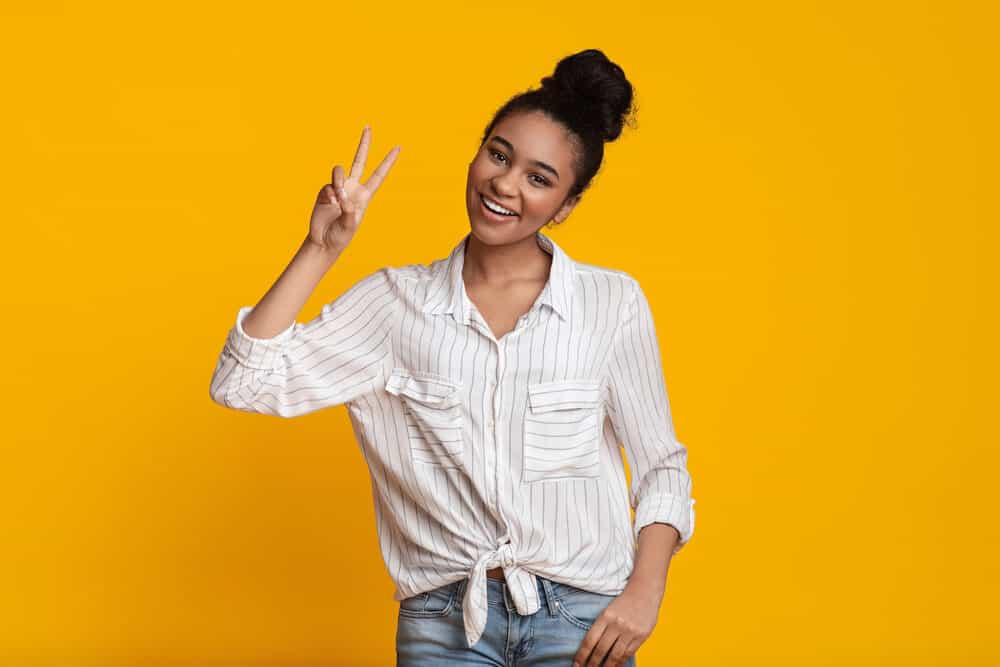 Black girl in casual clothes wearing a bun on top of her head with fine hair